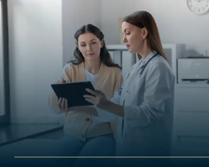 A female doctor using a tablet to explain coporate wellness to a patient in a clinical setting